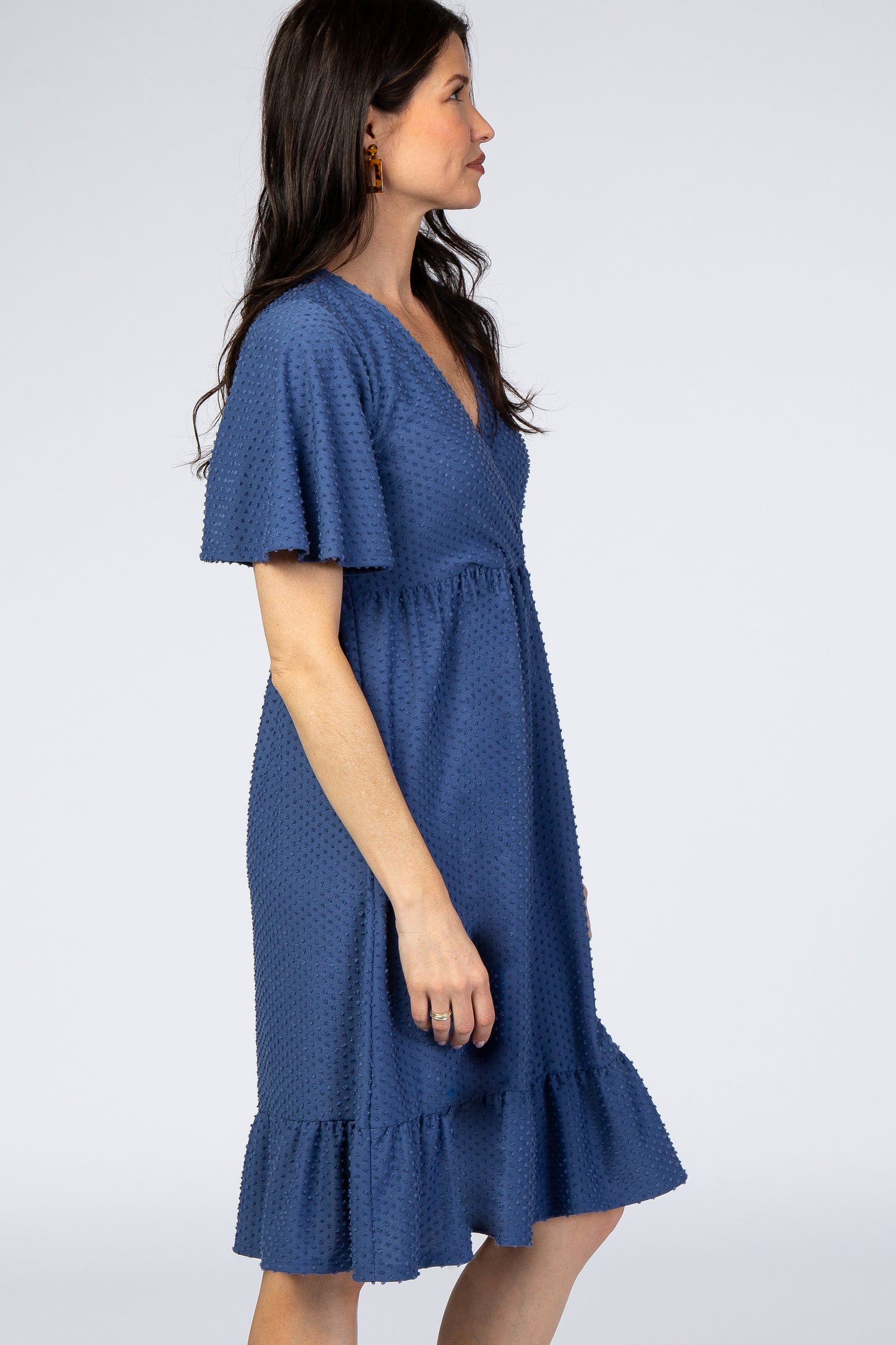 woman wearing a navy blue short sleeve dress with a ruffled hem and textured fabric