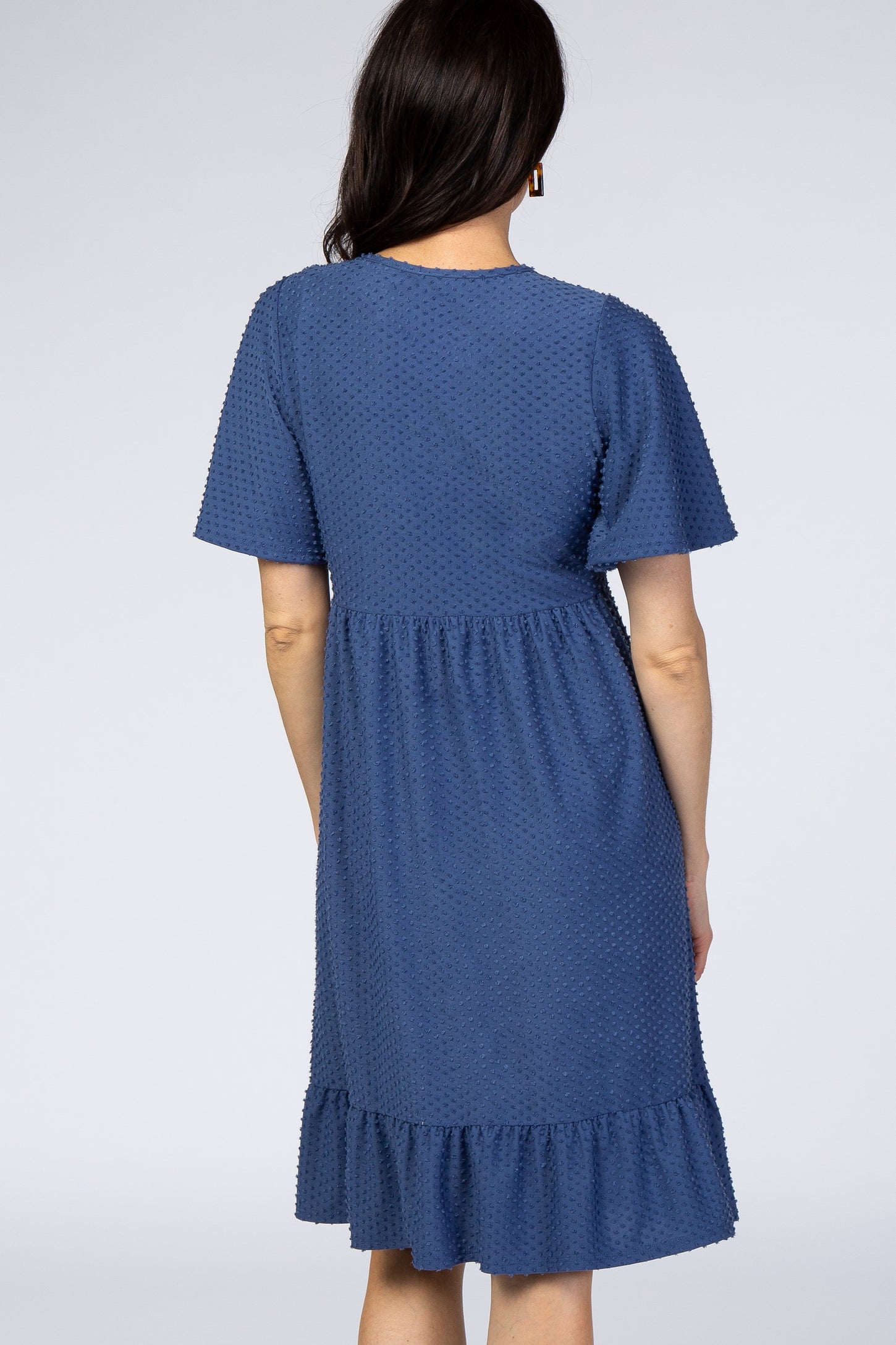 woman wearing a navy blue short sleeve dress with a ruffled hem and textured dot pattern
