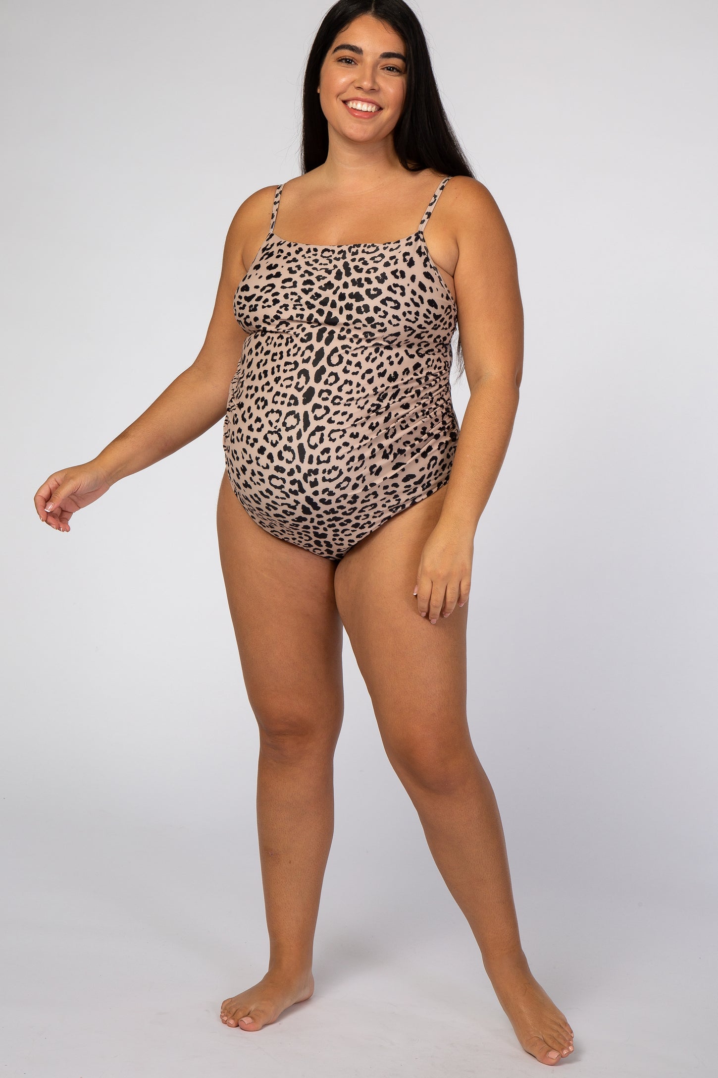 woman wearing a leopard print maternity one-piece swimsuit and showing her baby bump