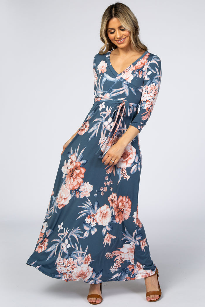 woman wearing a blue floral v-neck maternity maxi dress with three-quarter sleeves and a waist tie
