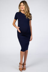 woman wearing a navy blue short sleeve maternity dress and holding her baby bump