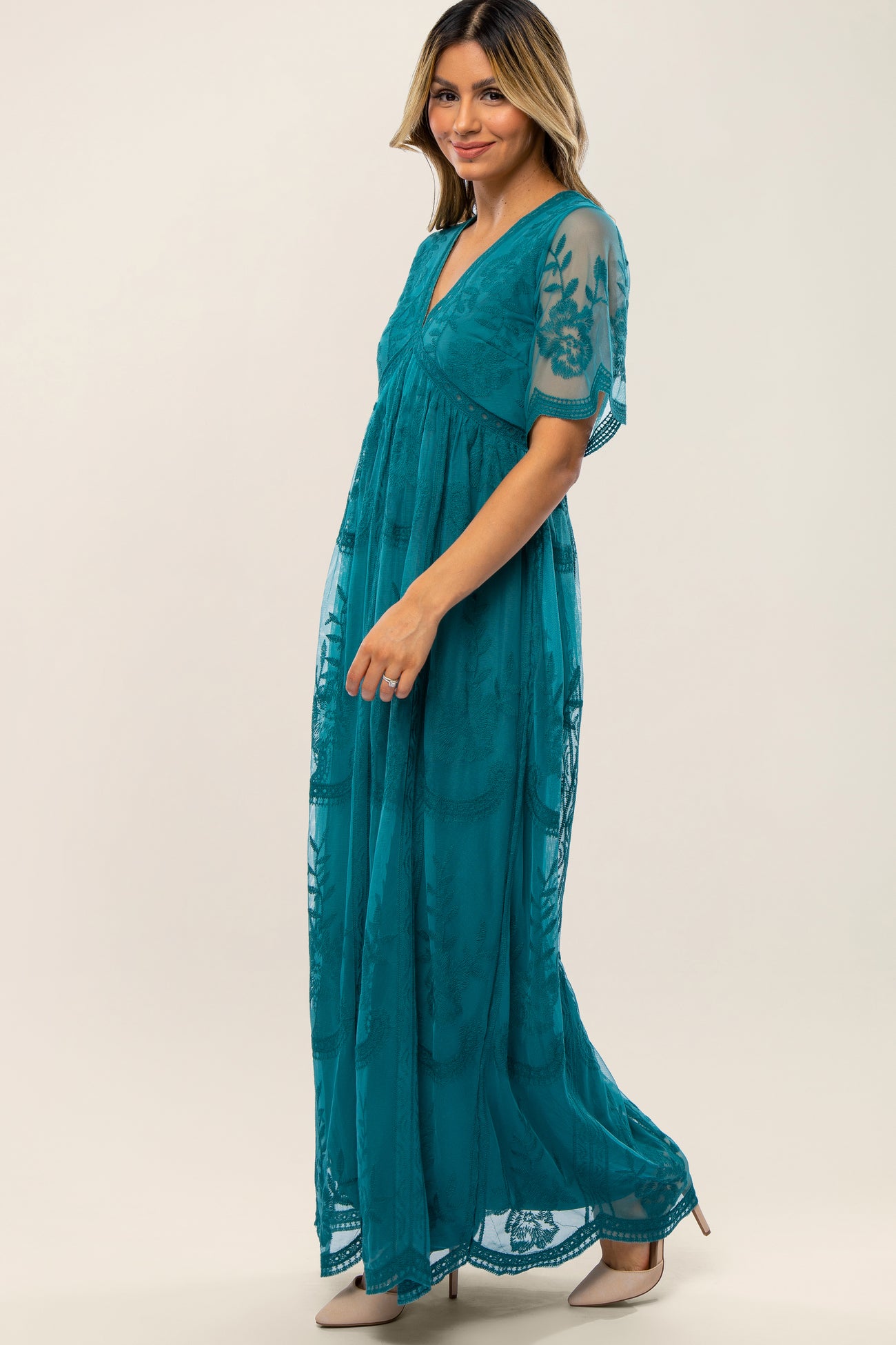 woman wearing a teal maxidress with sheer embroidered sleeves and a v-neckline