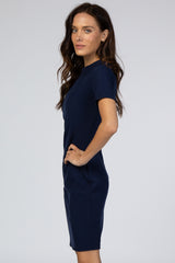 woman posing in a navy blue ribbed short sleeve dress against a gray background