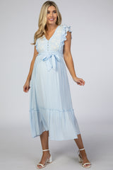 pregnant woman in light blue maternity midi dress with white floral embroidery and ruffle sleeves