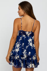 Woman wearing a navy blue floral print mini dress with spaghetti straps and a ruffled hem.