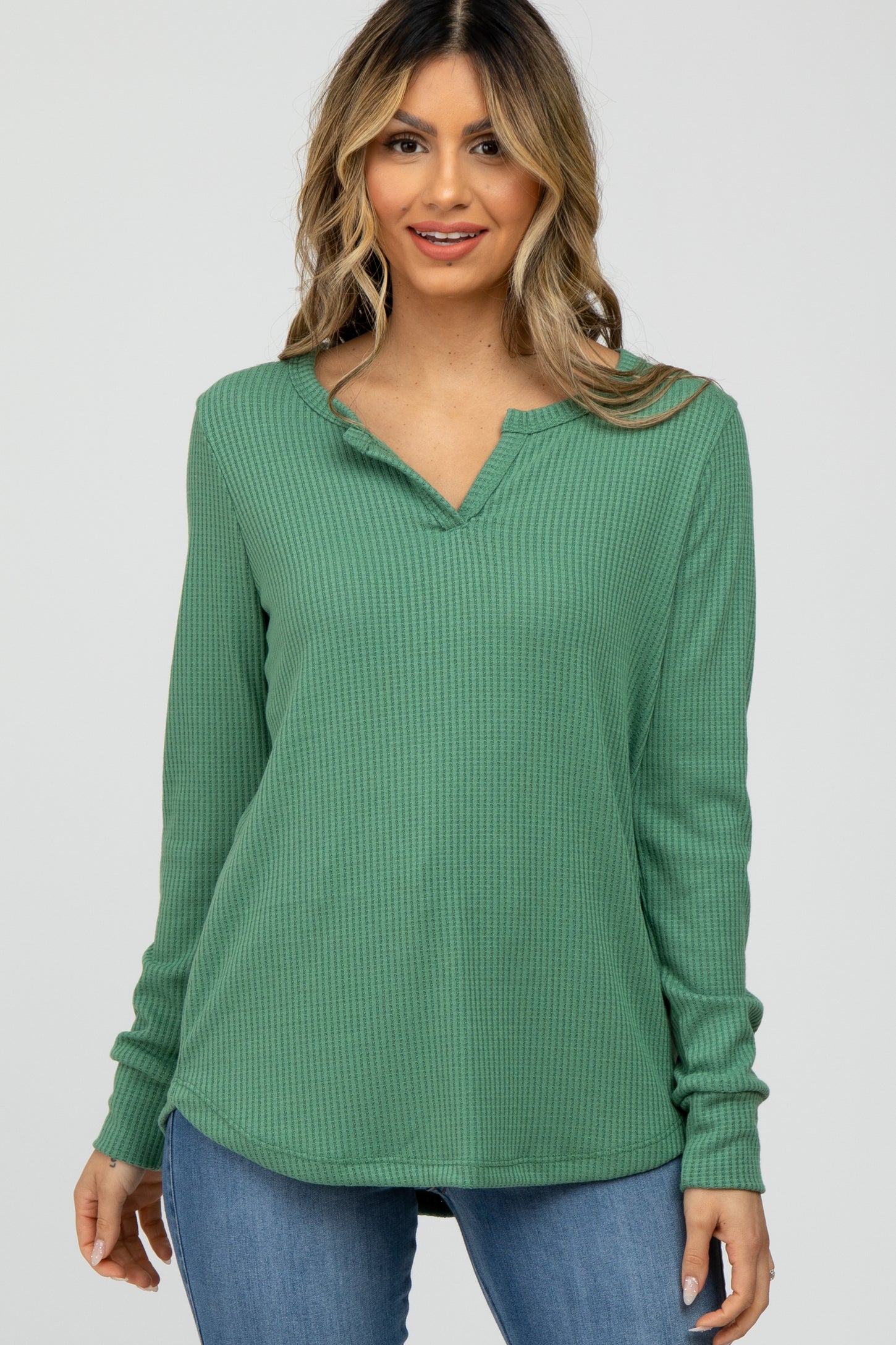 woman wearing a green long sleeve waffle knit henley top and blue jeans