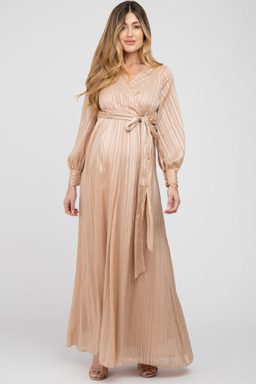 woman wearing a blush long sleeve wrap maternity dress with a tie waist and pleated fabric, showcasing her baby bump