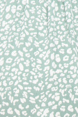 Close up of sage green fabric with white leopard print pattern