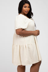 woman wearing a cream colored plus size puff sleeve tiered mini dress with textured fabric