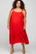 woman wearing a red maternity plus midi dress with adjustable tie straps and a ruffled hem, baby bump visible