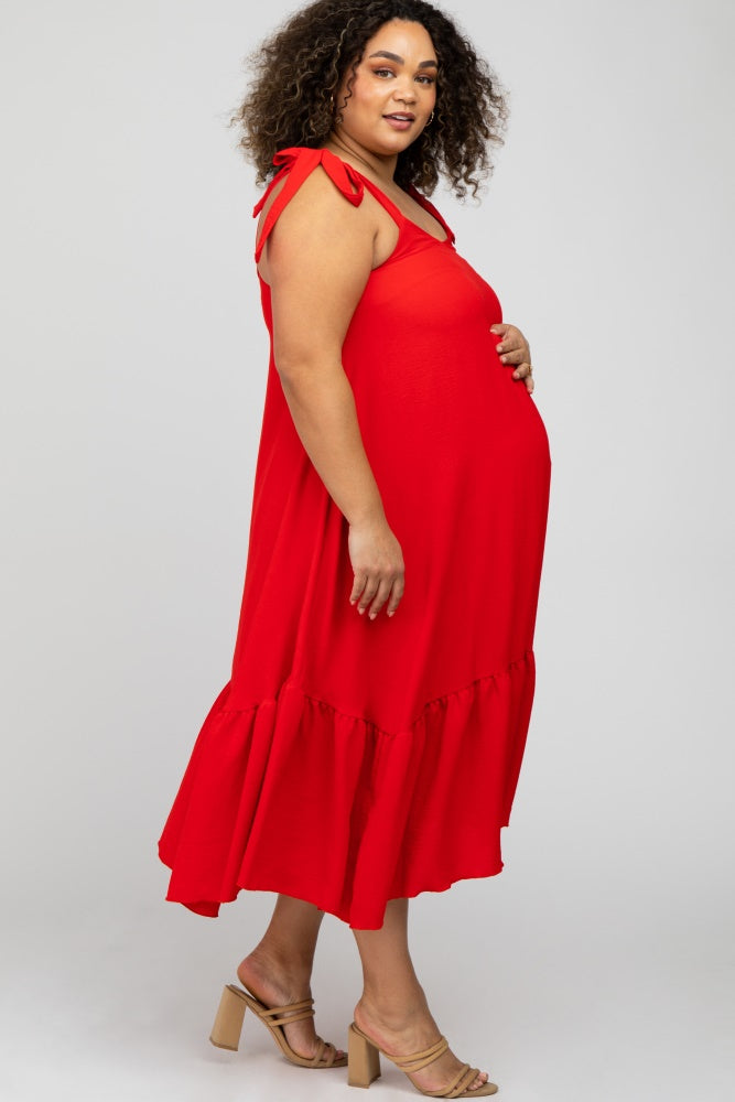 woman wearing a bright red maternity plus dress with tie straps and ruffled hem, showcasing her baby bump