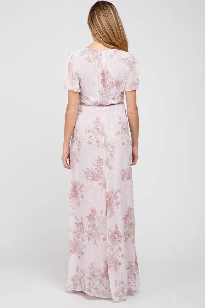 Back view of a woman wearing a light pink floral maxi dress with short flutter sleeves