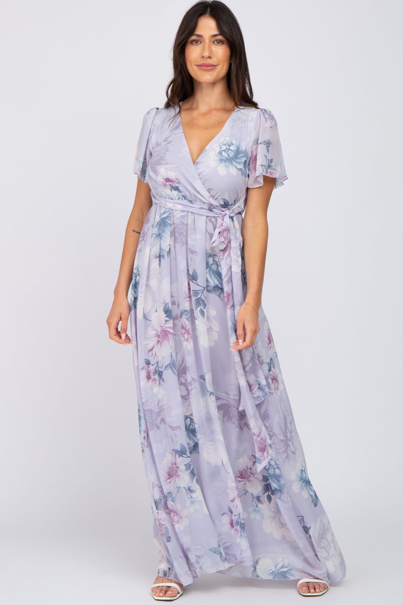 woman wearing a lavender floral wrap maxi dress with short flutter sleeves and a waist tie