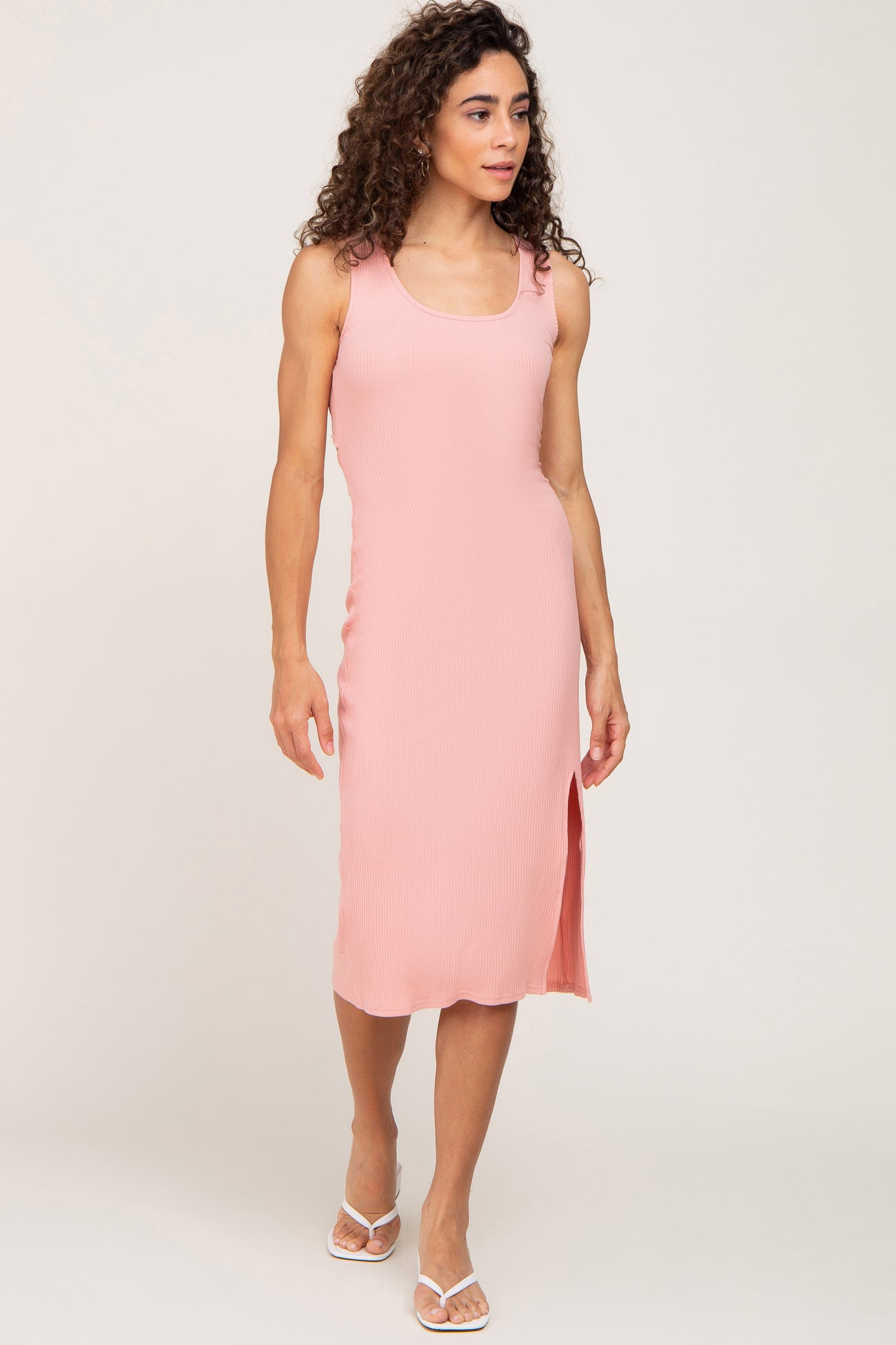 woman wearing a pink ribbed midi tank dress with a side slit and white flip flops