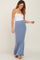 woman wearing a white spaghetti strap tank top and a light blue textured maxi skirt