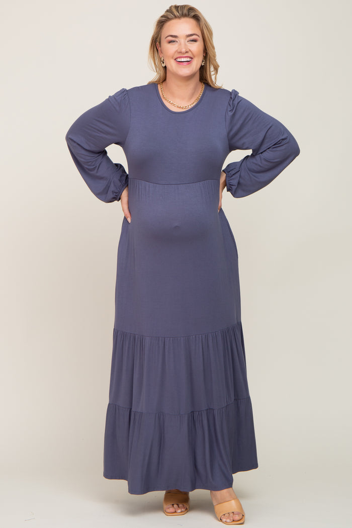 Smiling pregnant woman wearing a long sleeve blue tiered maternity maxi dress with a gold necklace