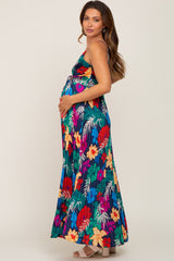 woman wearing a colorful floral maternity maxi dress and cradling her baby bump