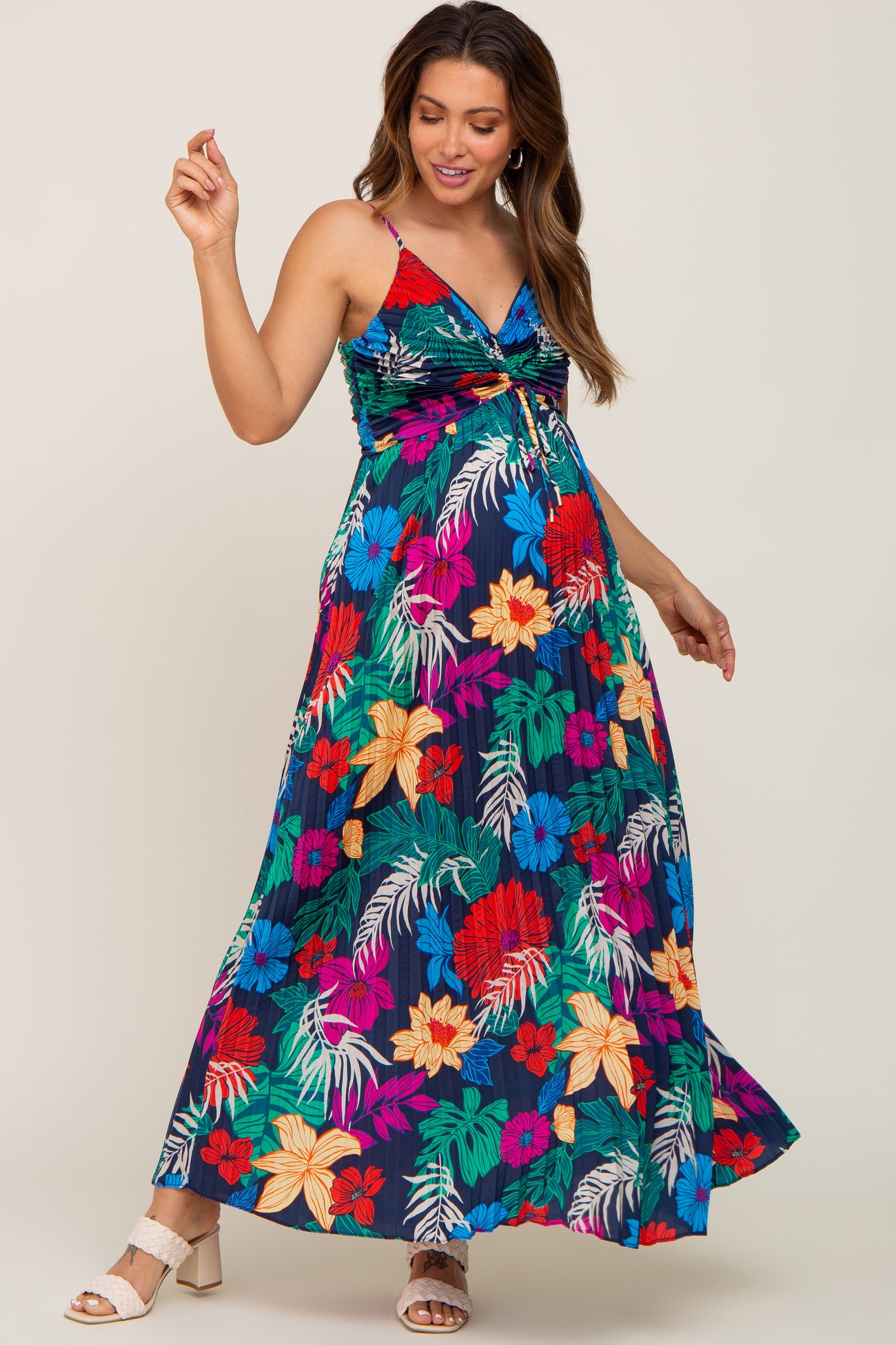 woman wearing a colorful floral maxi maternity dress with a twist front detail and a visible baby bump