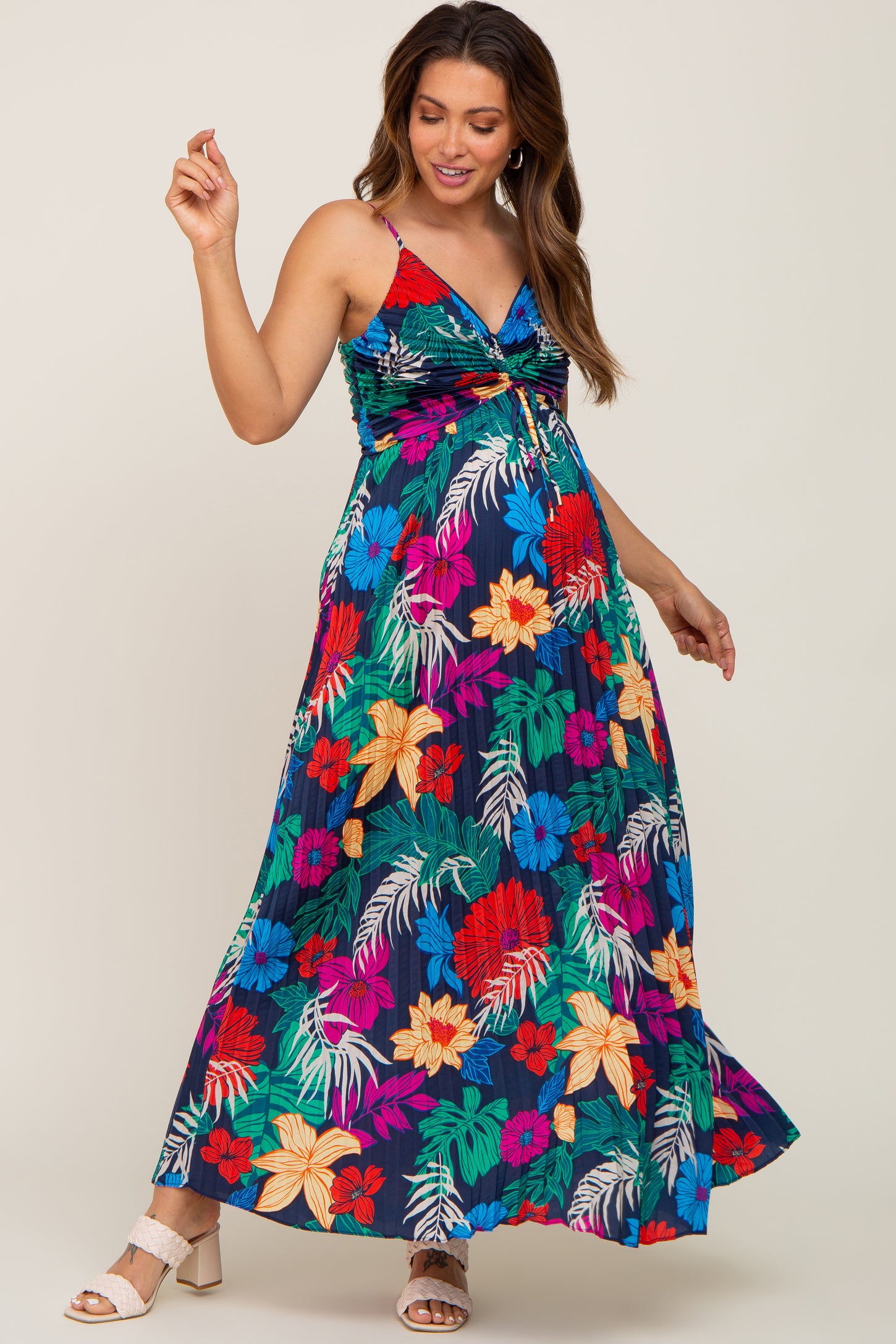 woman wearing a colorful floral maxi maternity dress with a twist front detail and a visible baby bump