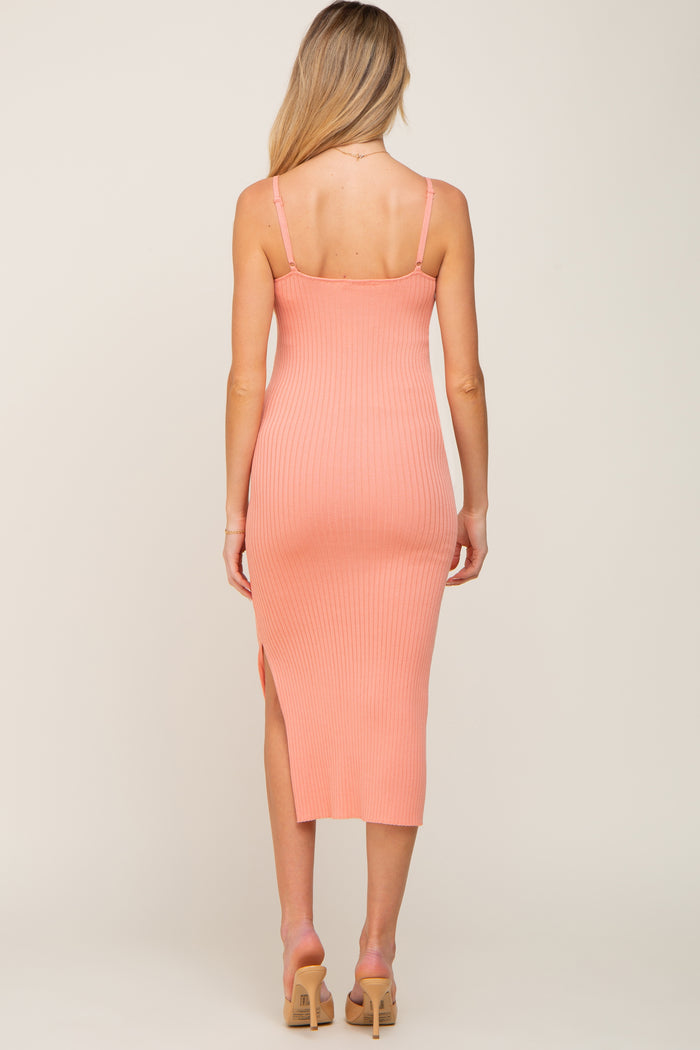 woman wearing a light pink ribbed midi maternity dress with a side slit and adjustable straps, showing her back