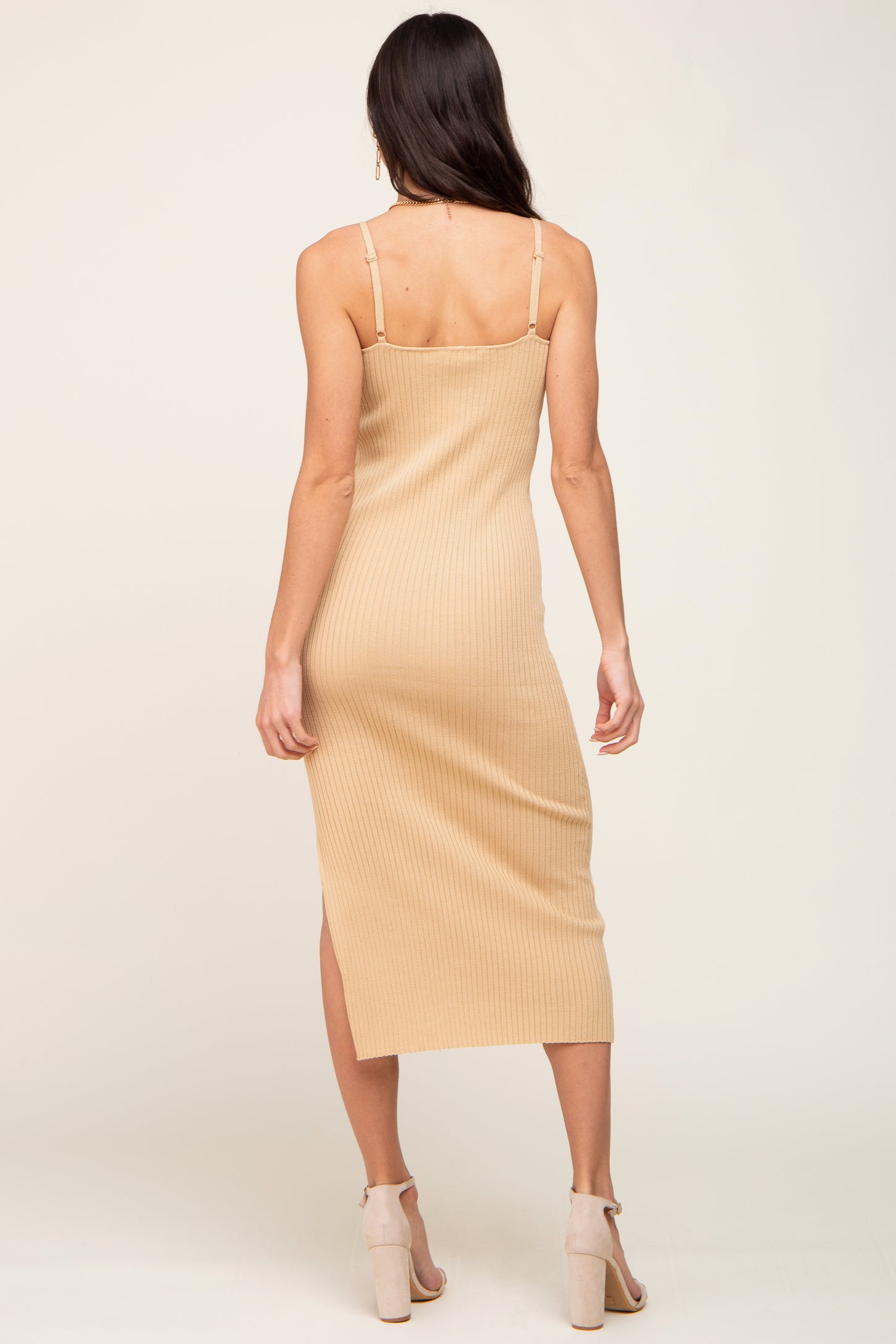 woman wearing a beige ribbed midi dress with spaghetti straps and side slit, viewed from the back