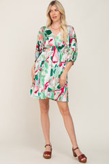 Woman wearing a green and pink marble print v-neck mini dress with three-quarter sleeves and brown sandals