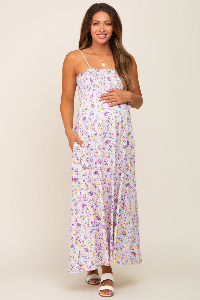 Pregnant woman wearing a purple floral smocked maternity maxi dress with spaghetti straps