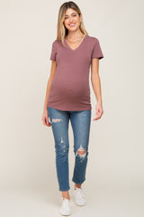 smiling pregnant woman wearing mauve v-neck maternity t-shirt and distressed blue jeans