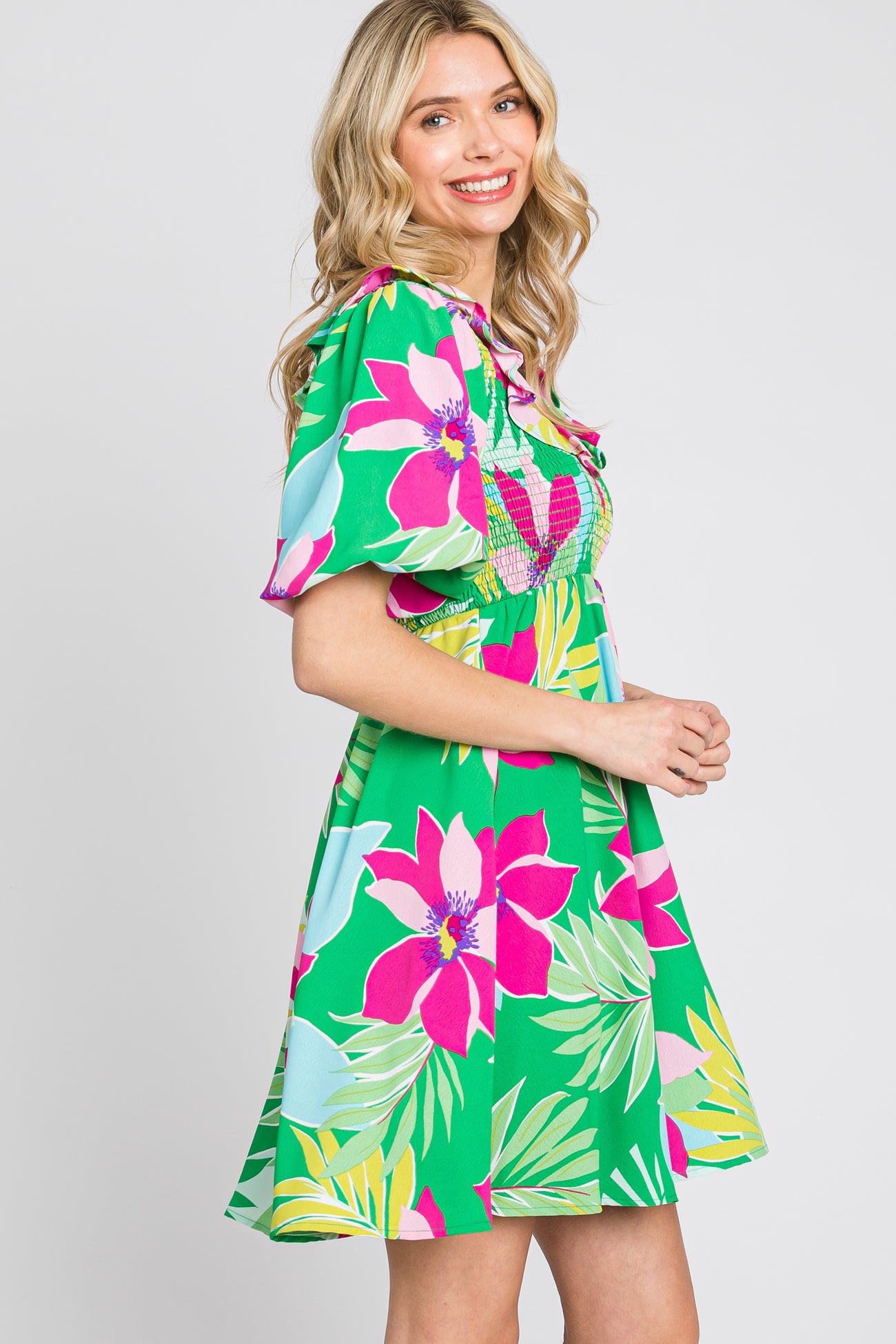 woman wearing a vibrant green floral dress with pink and blue patterns and short sleeves