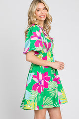 woman wearing a vibrant green floral dress with pink and blue patterns and short sleeves