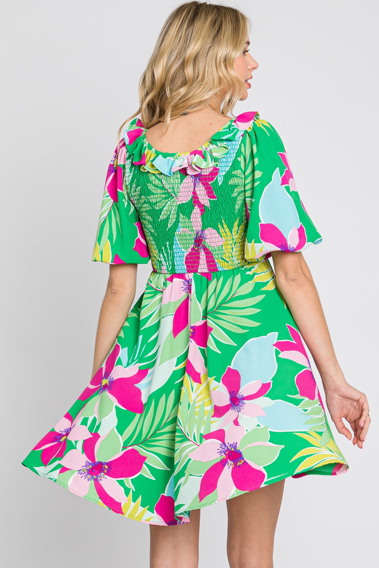 woman wearing a green floral print dress with short sleeves and a smocked back detail