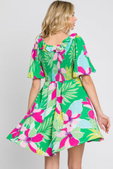 woman wearing a green floral print dress with short sleeves and a smocked back detail