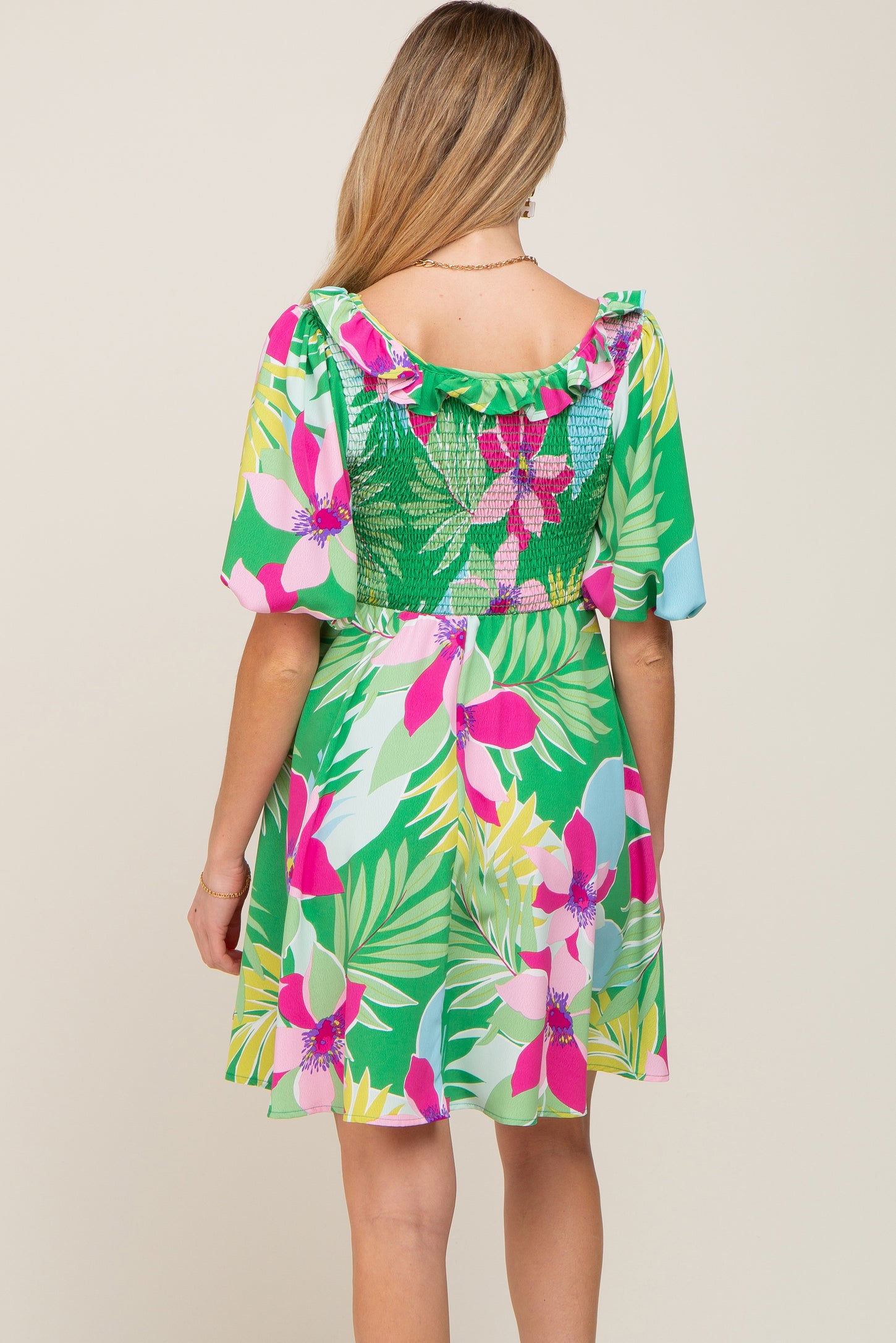 woman wearing a floral print green maternity dress with ruffled shoulders and a smocked back