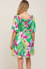 woman wearing a floral print green maternity dress with ruffled shoulders and a smocked back