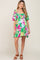 woman wearing a green floral maternity dress with puff sleeves and ruffle details, showcasing her baby bump