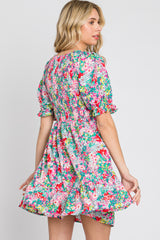 Woman wearing a colorful floral mini dress with a smocked bodice and puff sleeves against a white background