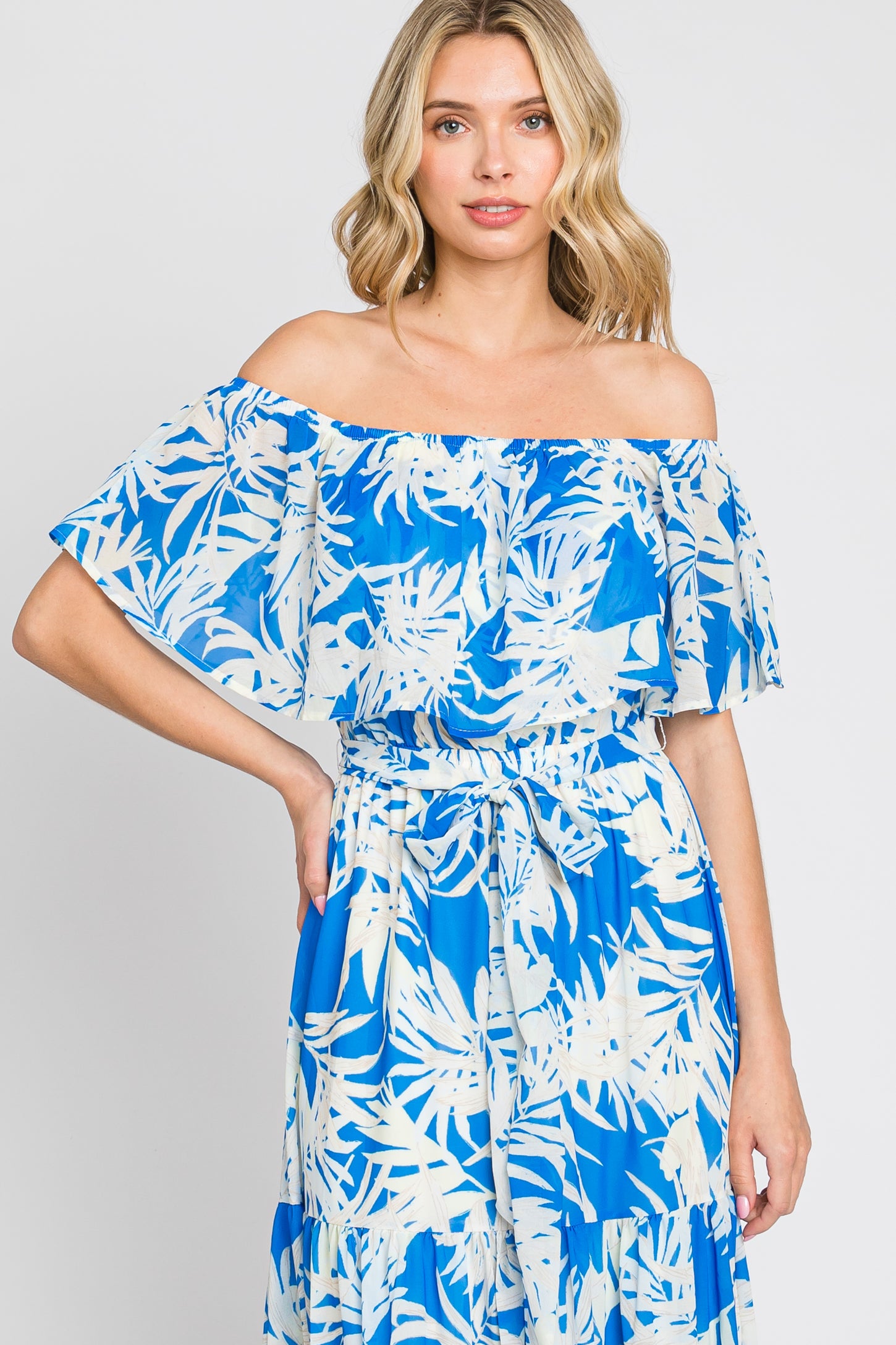 woman wearing a blue off-the-shoulder dress with white floral print and ruffled sleeves