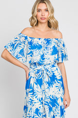 woman wearing a blue off-the-shoulder dress with white floral print and ruffled sleeves