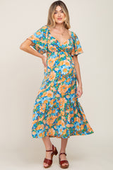 woman wearing a blue floral maternity dress with a flowy skirt and short sleeves, showing her baby bump