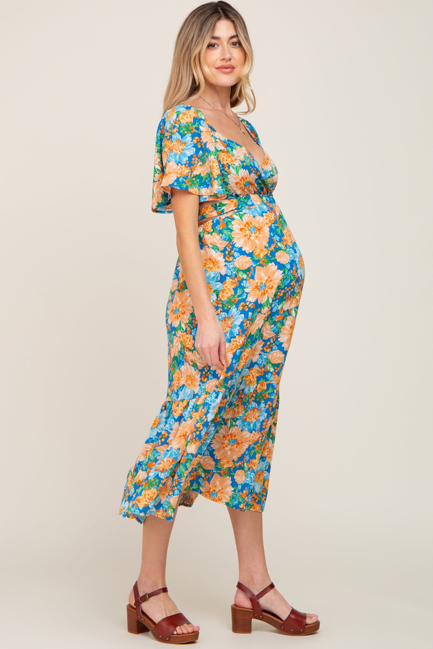 woman wearing a floral maternity dress with a v-neckline and short sleeves, showing her baby bump