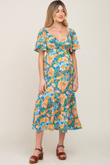 woman wearing a floral maternity dress with flutter sleeves and a ruffled hem, showcasing her baby bump