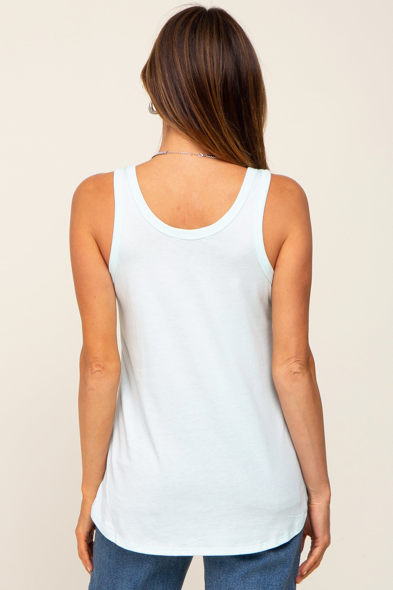 back view of a woman wearing a light blue scoop neck tank top and blue jeans