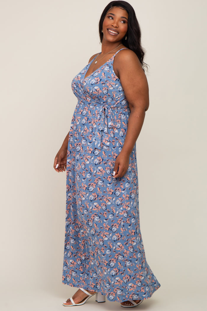 smiling woman wearing a blue floral sleeveless maxi dress with a waist tie and white sandals