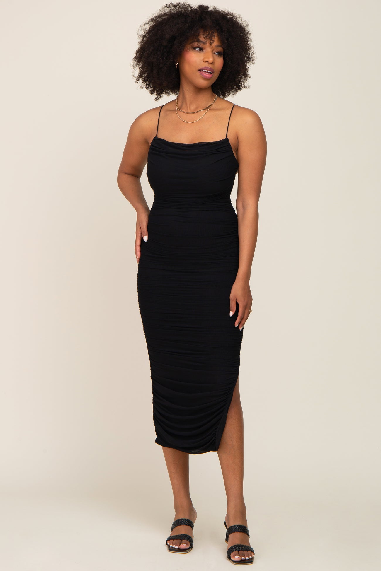 woman wearing a black fitted midi dress with ruched detailing and adjustable spaghetti straps