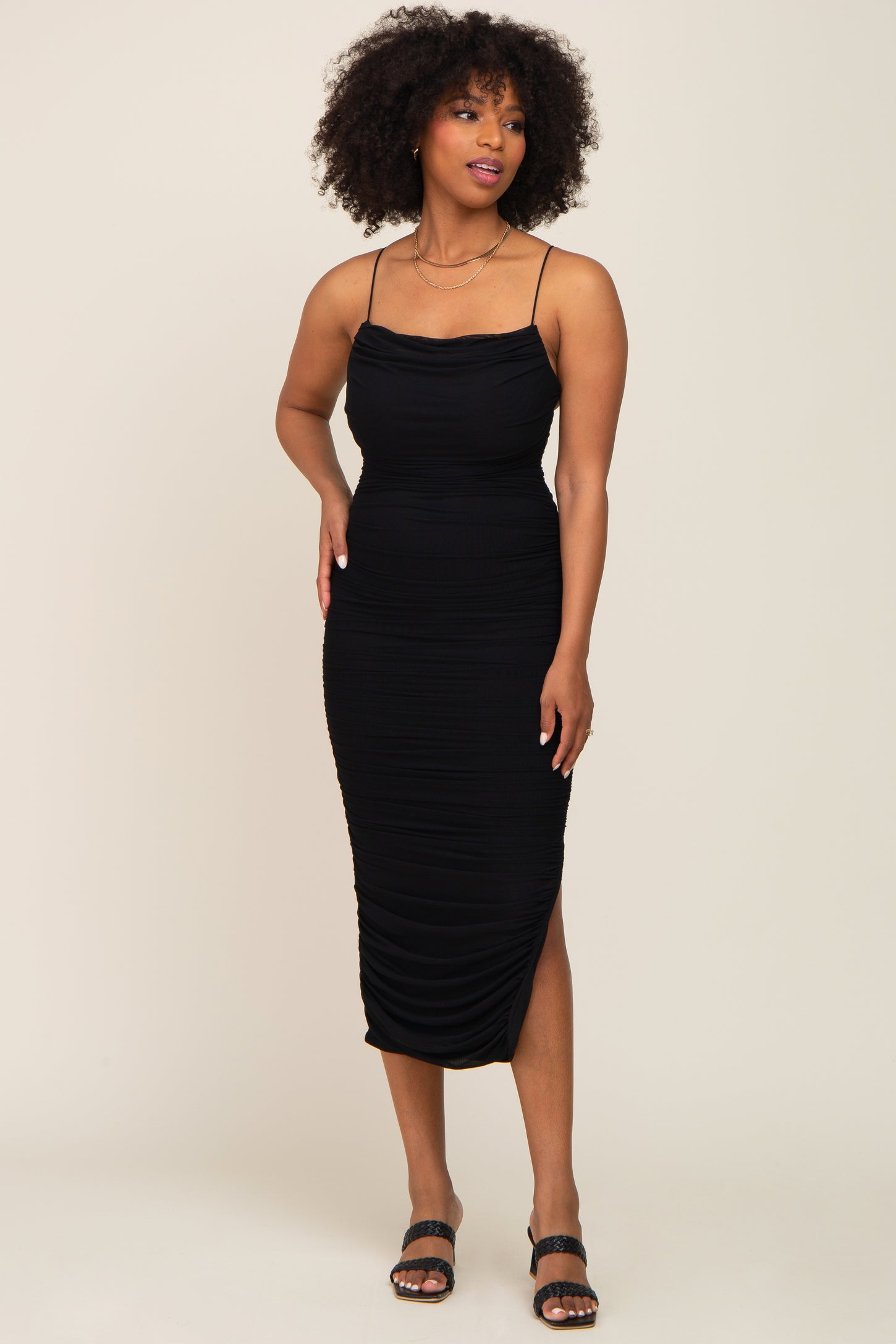 woman wearing a black fitted midi dress with ruched detailing and adjustable spaghetti straps