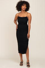 woman wearing a black fitted midi dress with ruched detailing and adjustable spaghetti straps