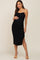 woman wearing a black ruched maternity dress with a side slit and adjustable spaghetti straps, showcasing her baby bump