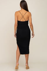 woman wearing a black ruched maternity dress with a back split and crisscross straps