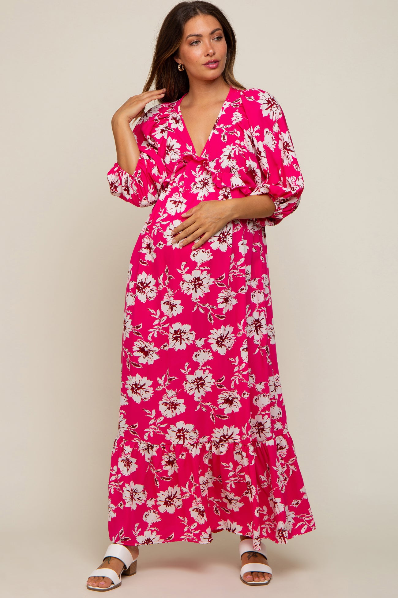 woman wearing a pink floral maxi maternity dress and holding her baby bump
