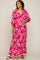 woman wearing a pink floral maternity maxi dress with a deep v-neck and ruffled hem, holding her baby bump